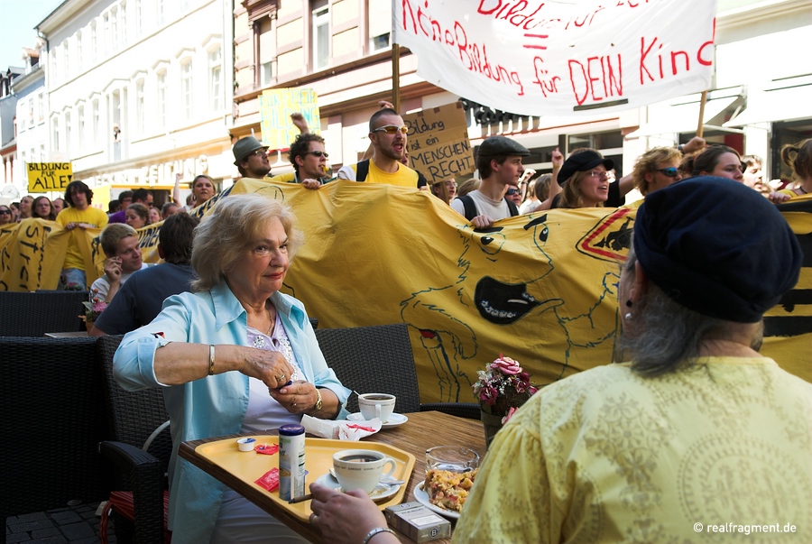 Demonstranten ziehen an Cafehausgästen vorbei