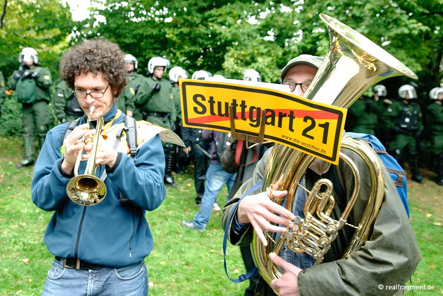 Protestler musizieren vor einer Polizeikette