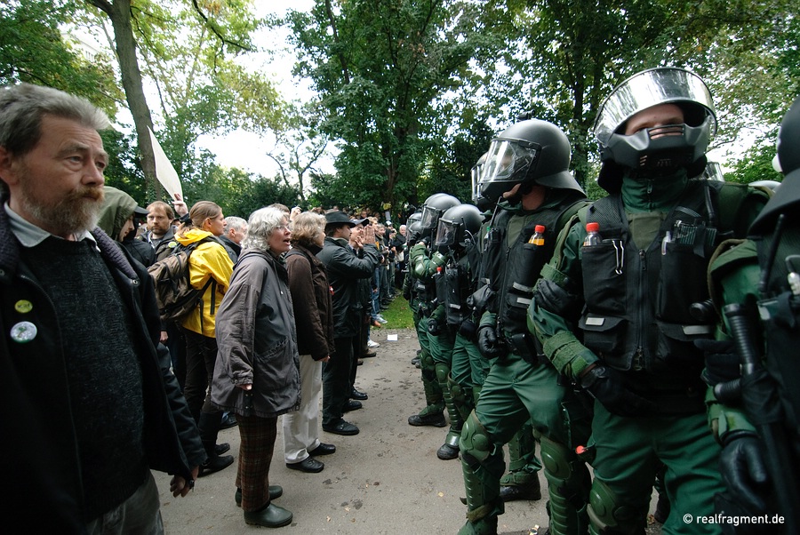 Indignant citizens are standing opposite to helmeted police