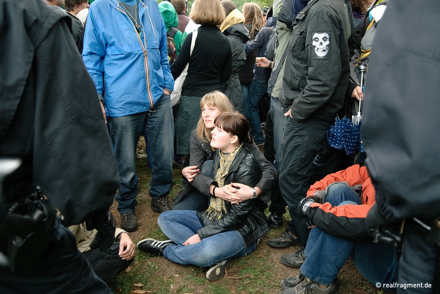 Two women are sitting down in front of a police line